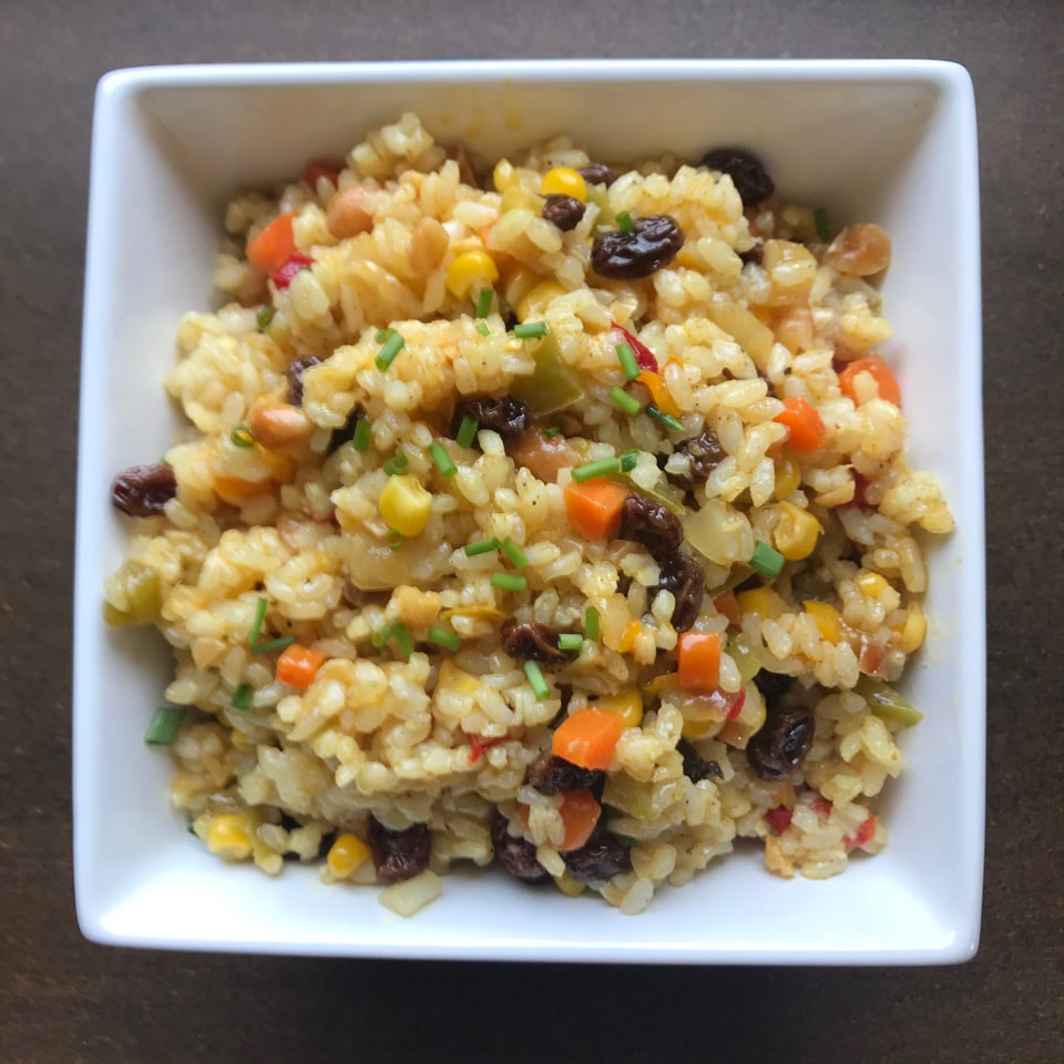A rice mixture with carrots and currants in a square white dish